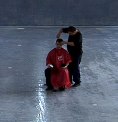 Still from Ordos 100, of Ai Weiwei cutting hair,